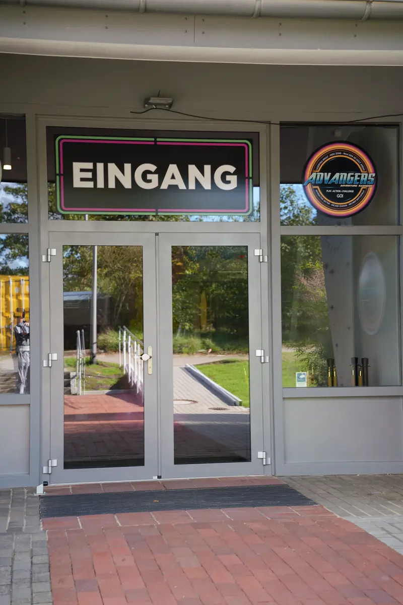 Eingang von Advangers in Buchholz in der Nordheide: Glastür mit dem Schild „Eingang“ und dem Advangers-Logo